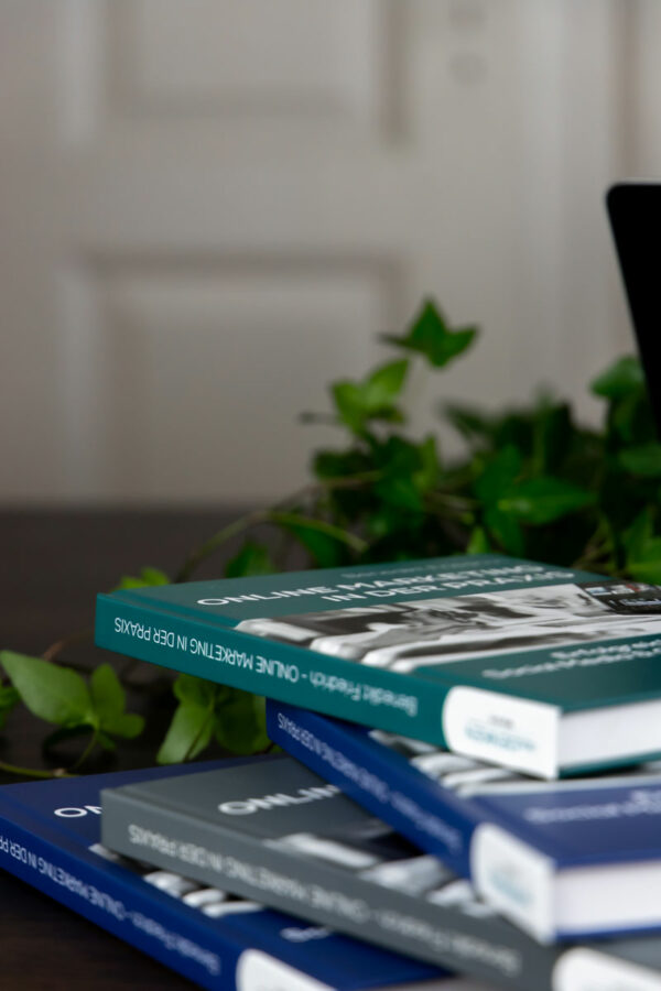 Bücherstapel im Vordergrund, Pflanze im Hintergrund